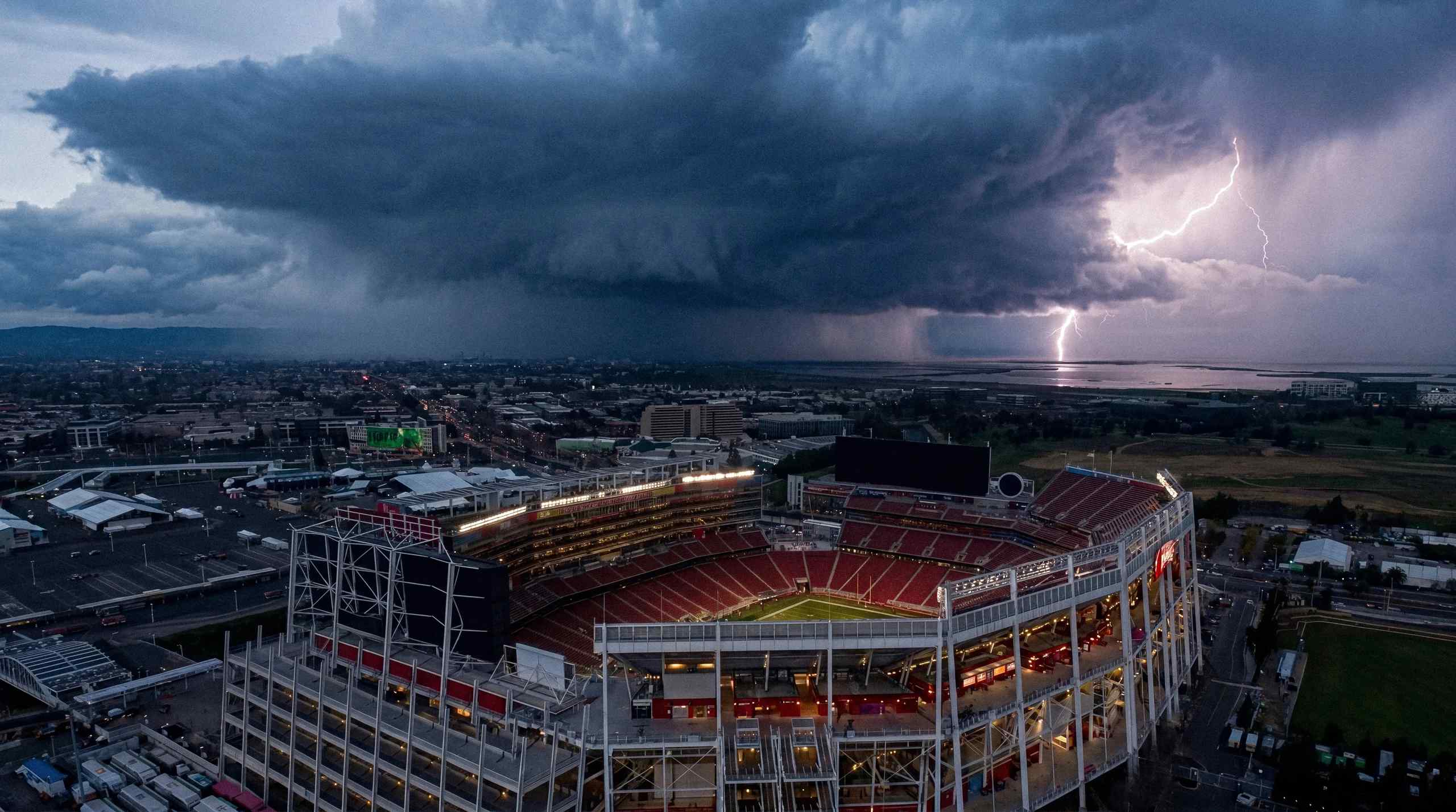 A massive storm brewing in the background of a sports stadium.